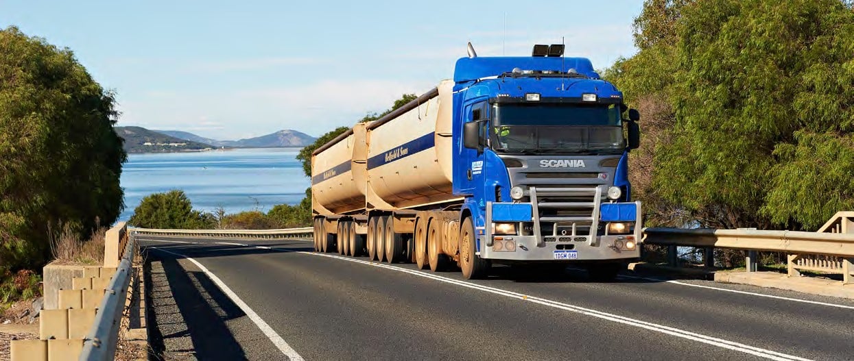 heavy vehicle with two trailers and the ocean in the background