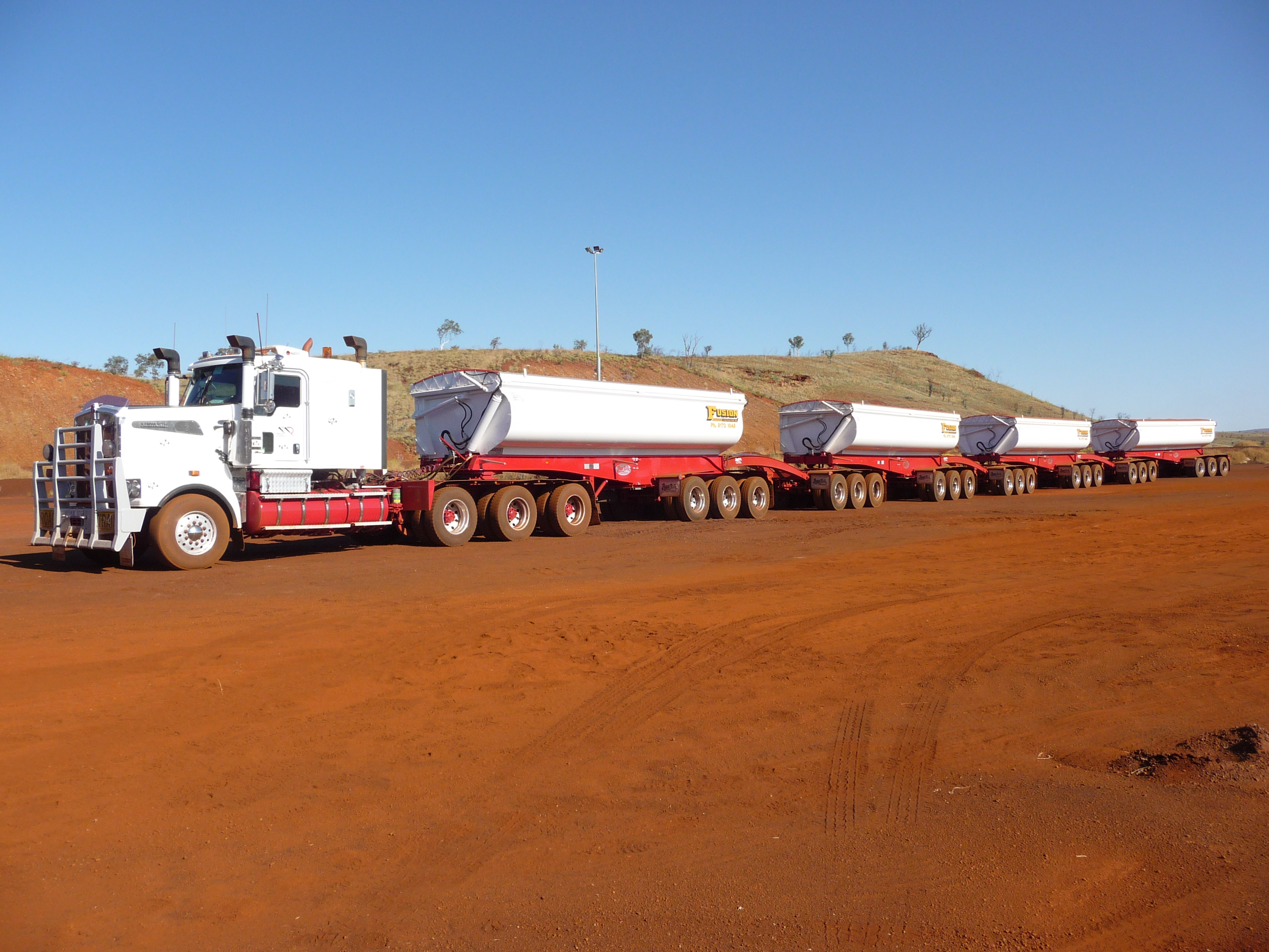Long Heavy Vehicle with four trailers, classed as a PBS vehicle, parked on a dirt road