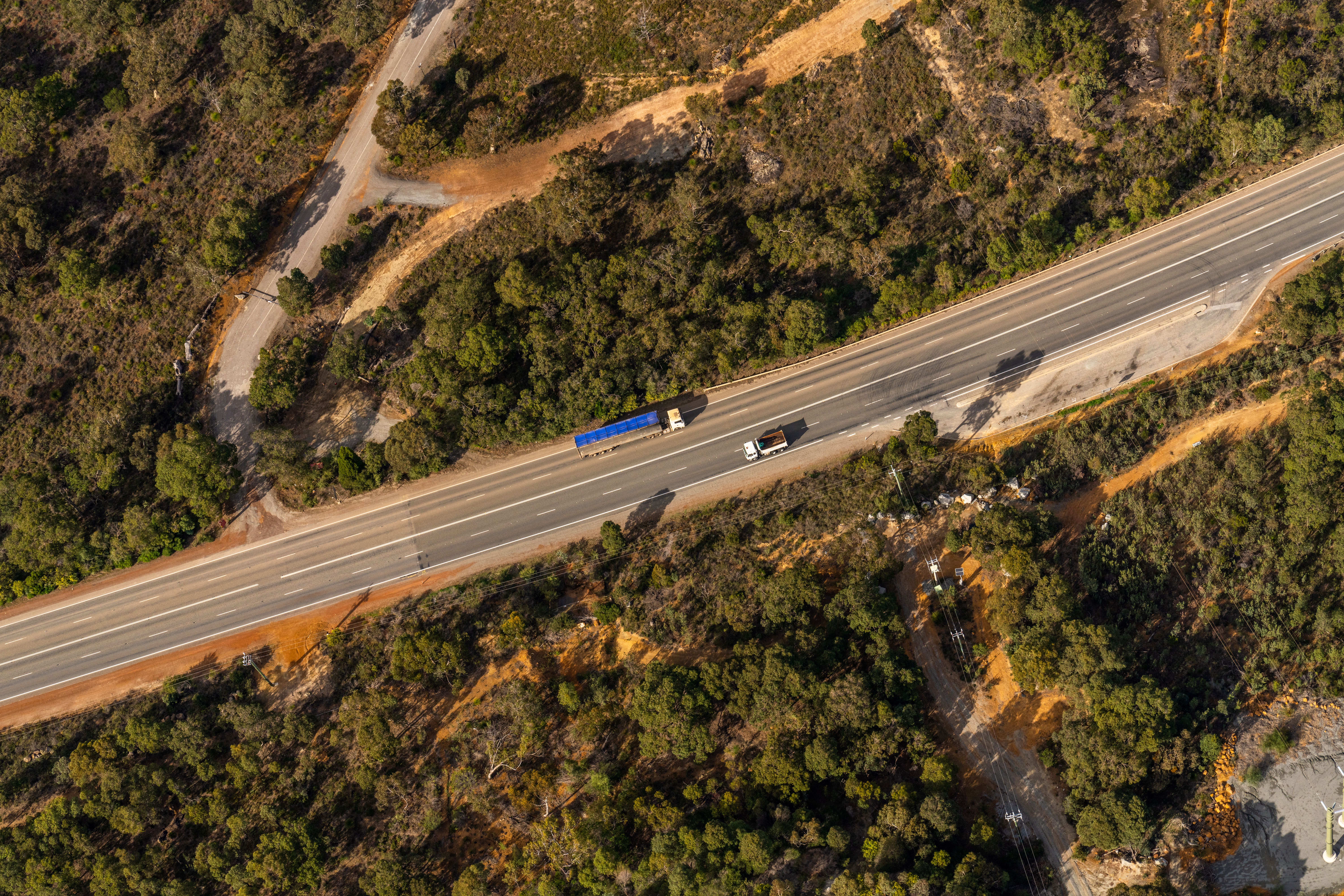Two trucks pictured driving along a road in opposite directions from above