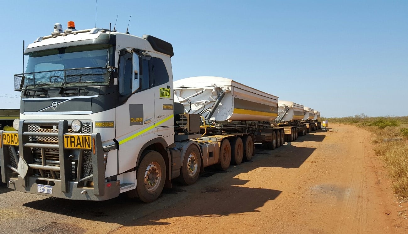 side view of a long Road Train with four trailers parked on the side of a road