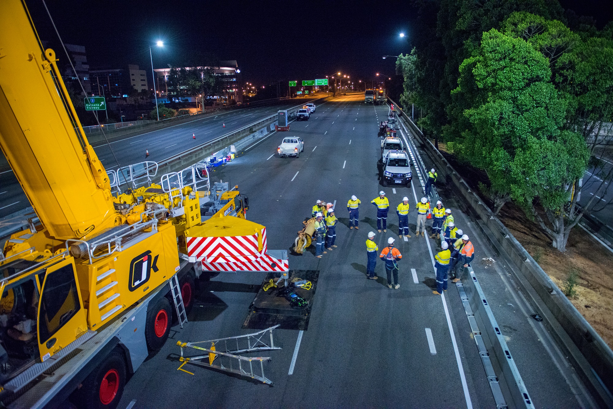 Crane and a group of construction workers on the road at night