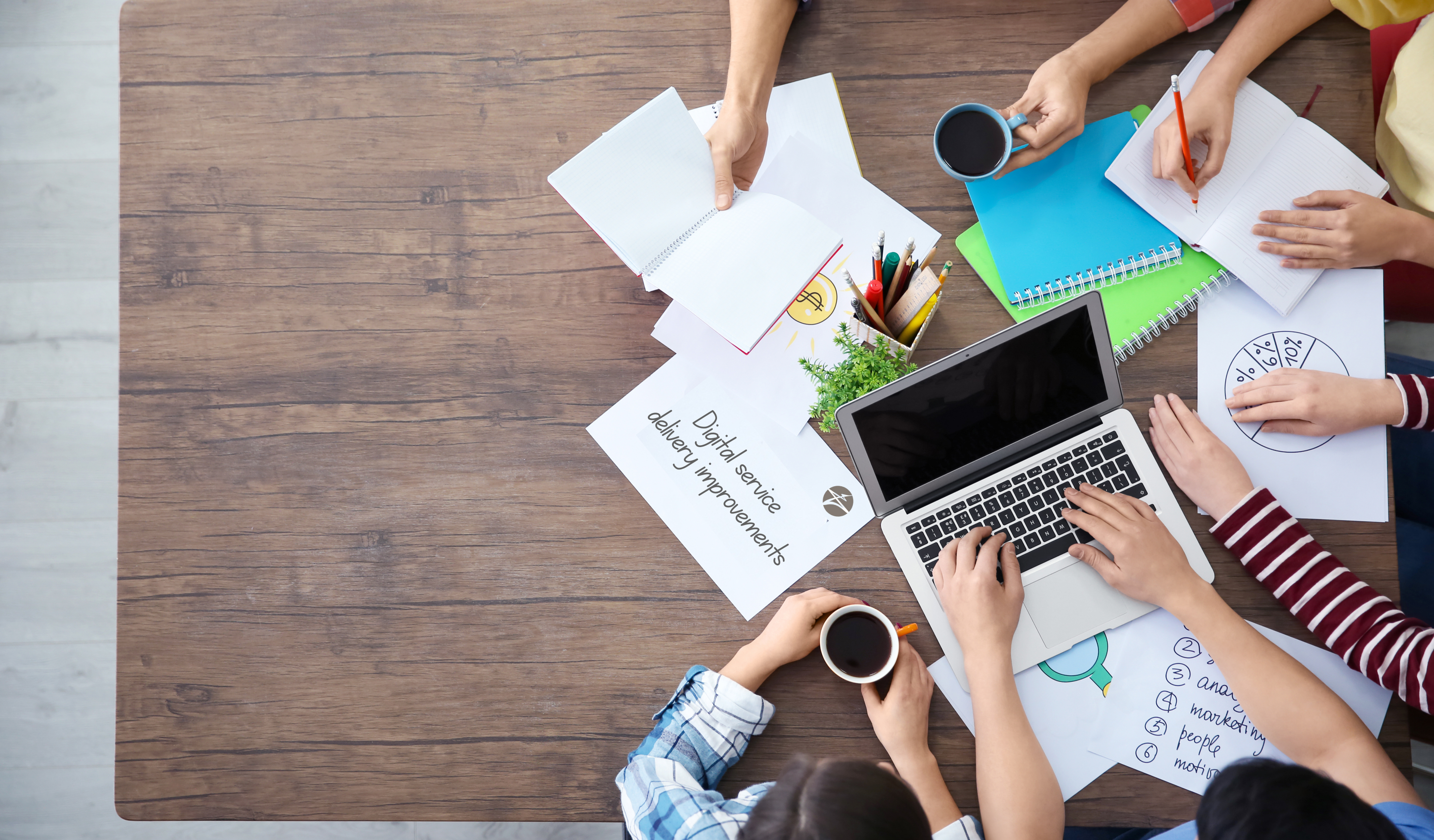 Aerial view of people sitting at a table with a laptop and papers
