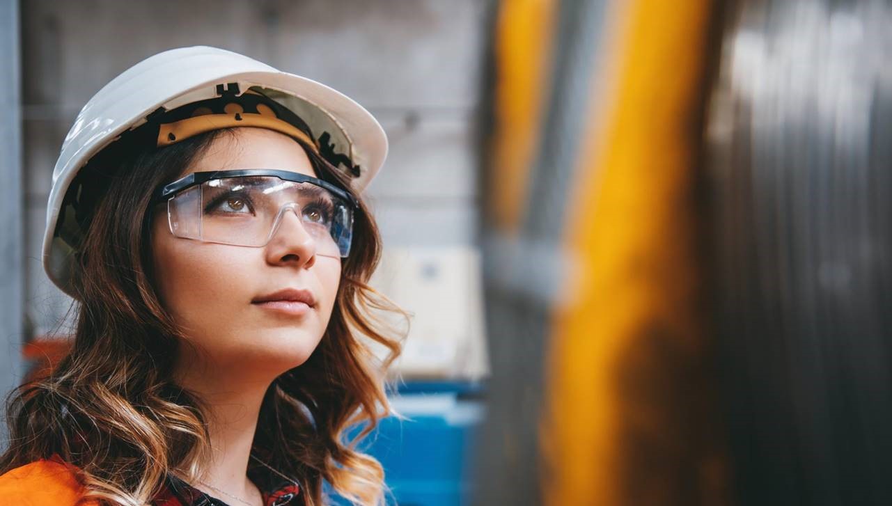 Female worker wearing a hard hat and protection glasses 