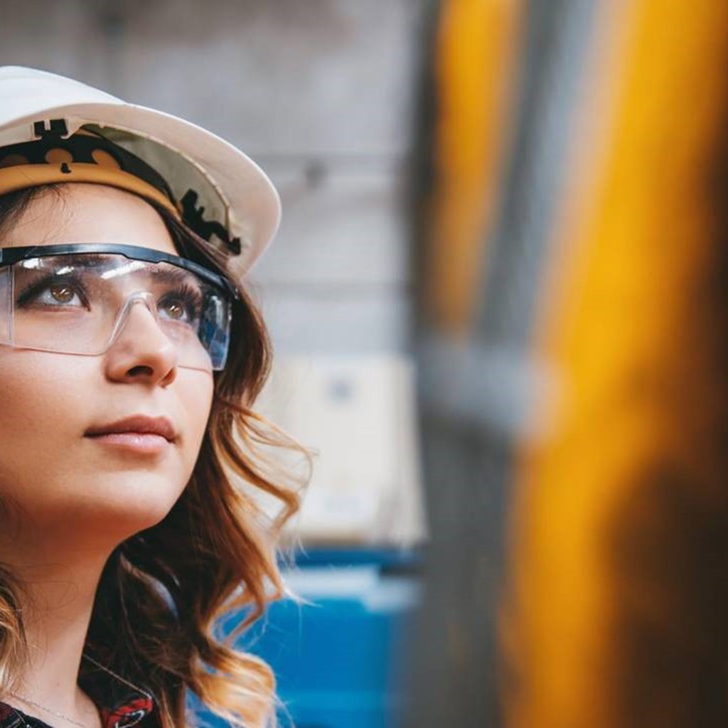 Female worker wearing a hard hat and protection glasses