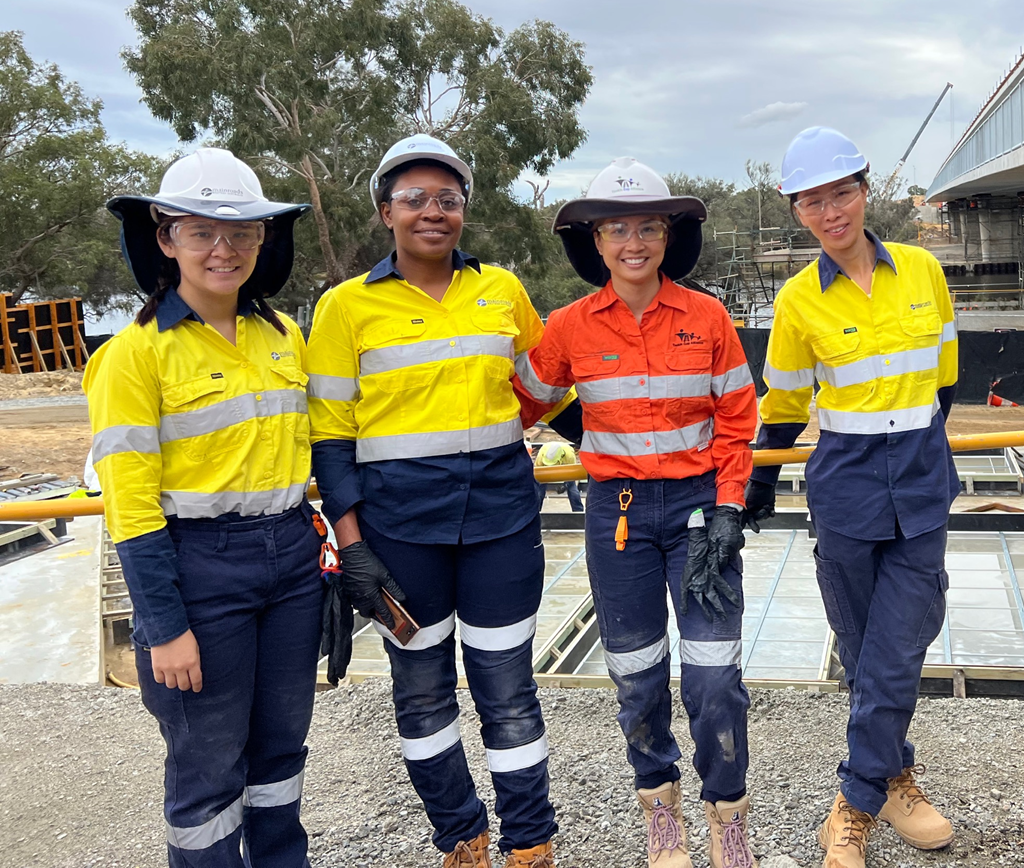 Four female engineers in personal protective equipment at a construction site
