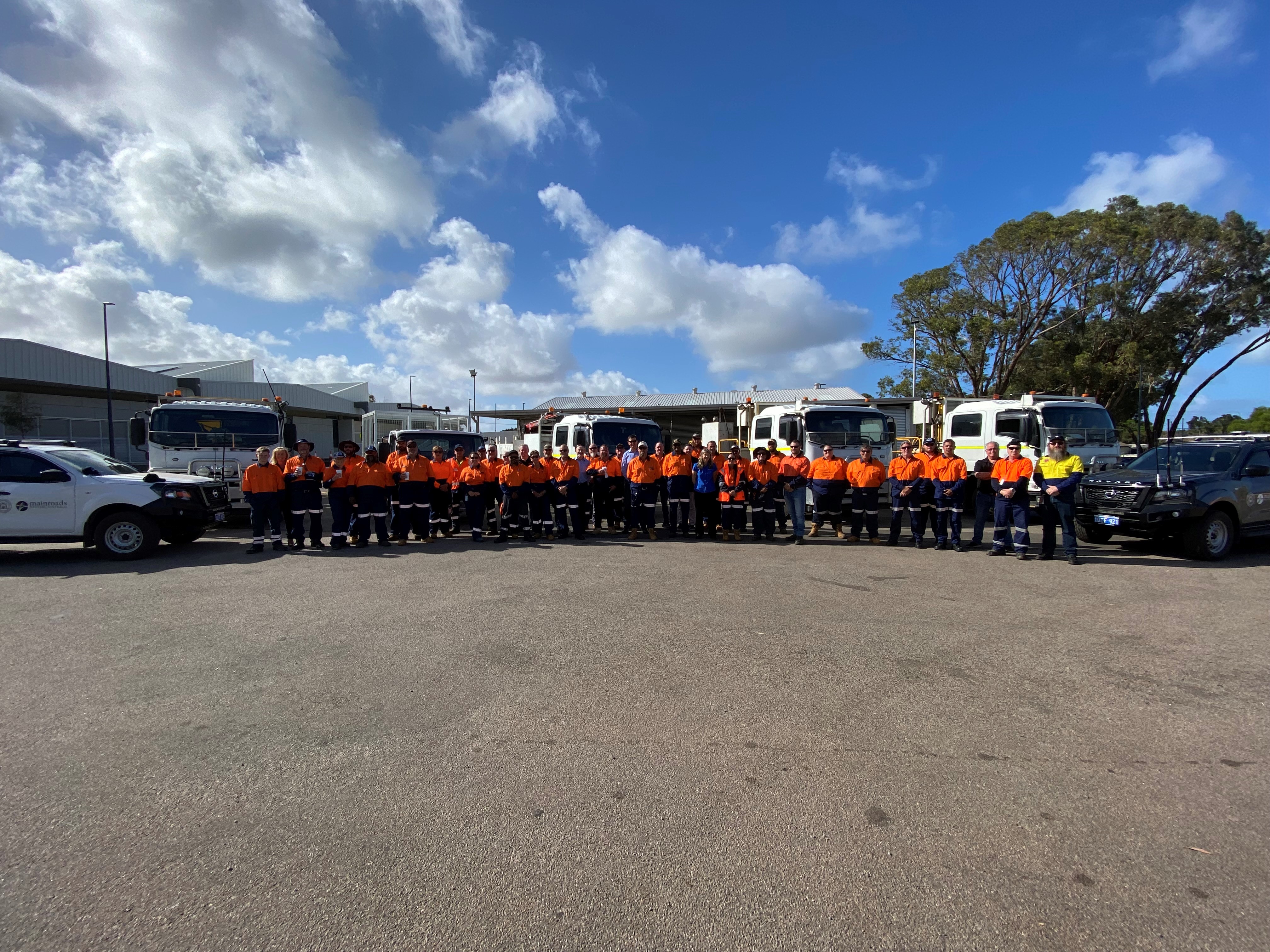 Group of people standing in front of trucks and cars