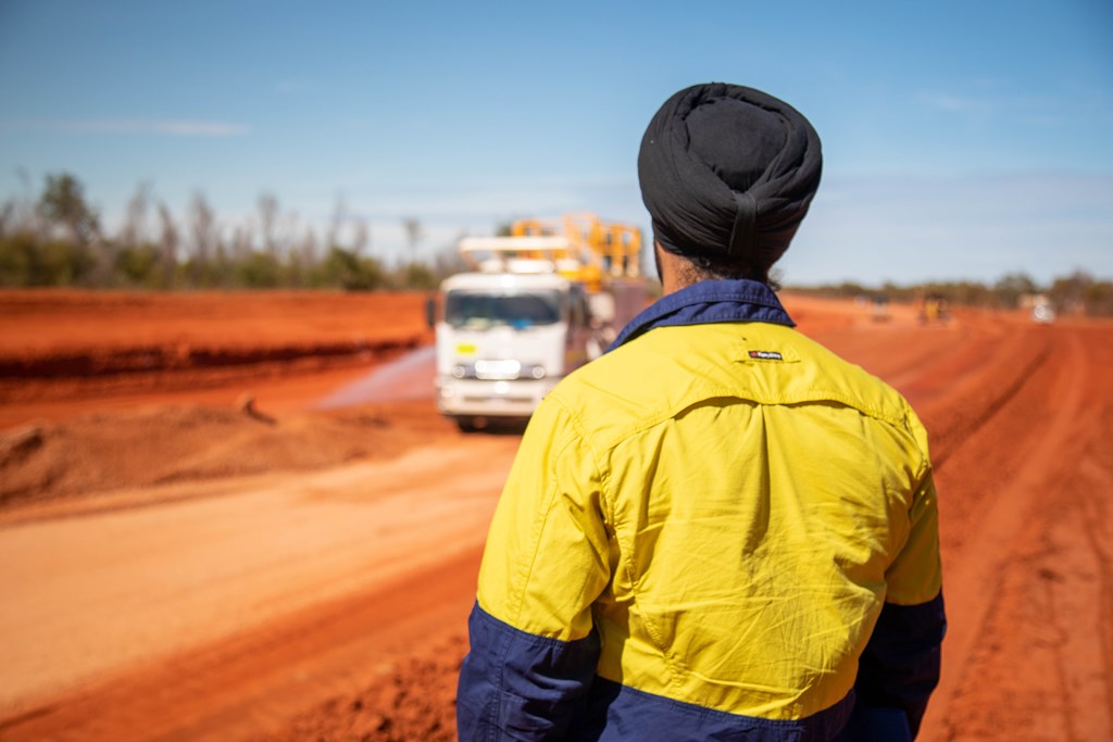 Construction worker standing in a rural area - facing a truck in a blurry background