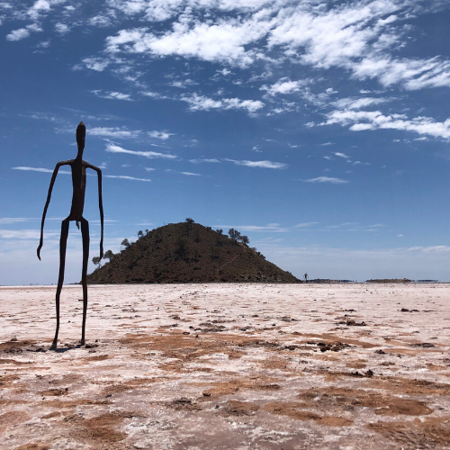 Statue facing a mountain in the background on the beach in a region