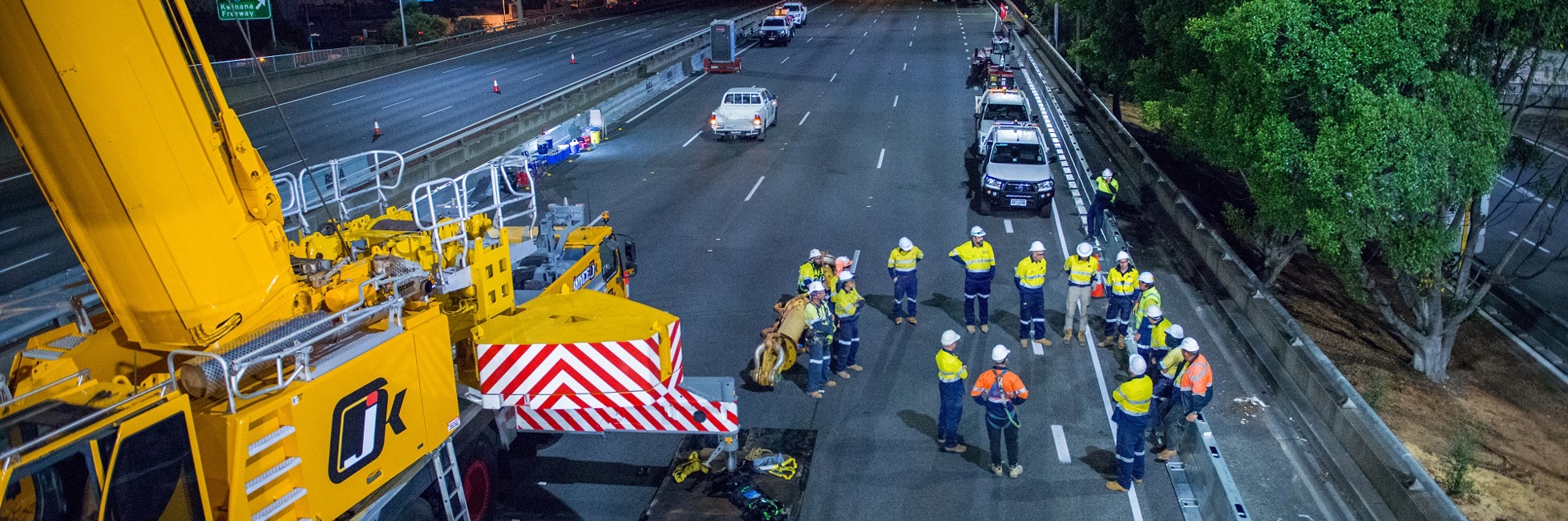 Crane and a group of construction workers on the road at night