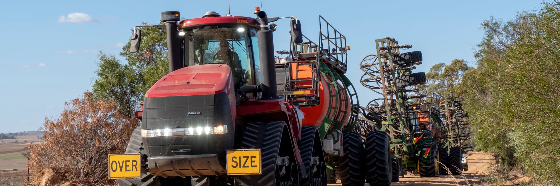 Agricultural Vehicle similar to a tractor towing agricultural machinery along a dirt road