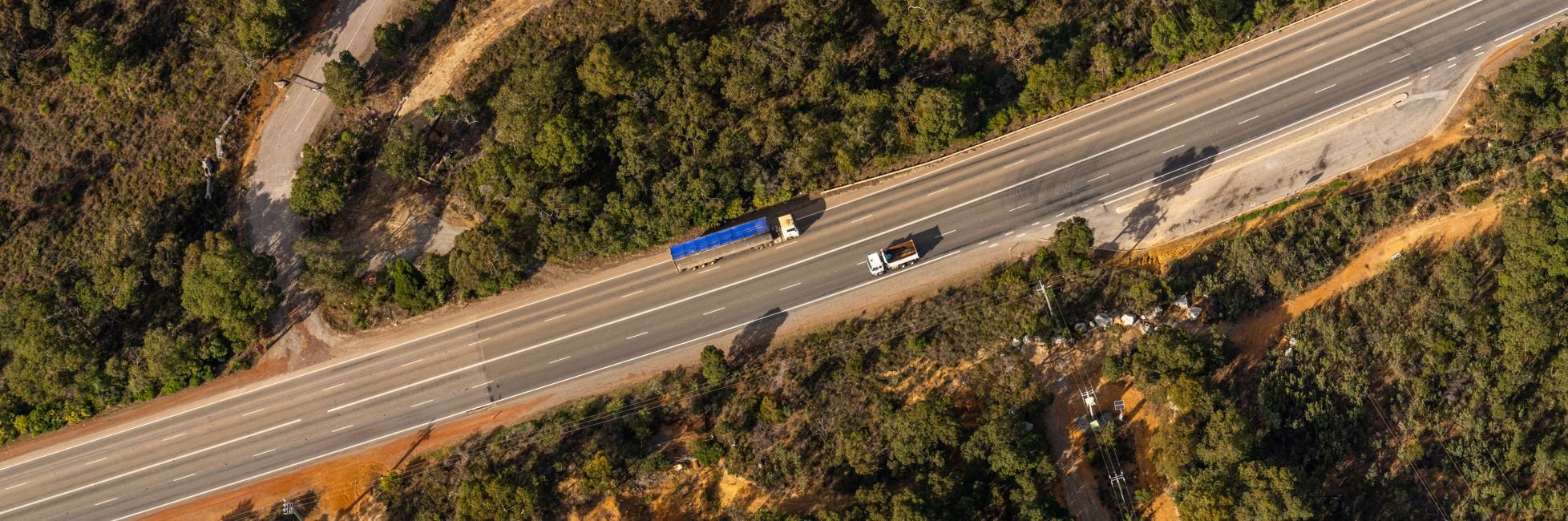Two trucks pictured driving along a road in opposite directions from above