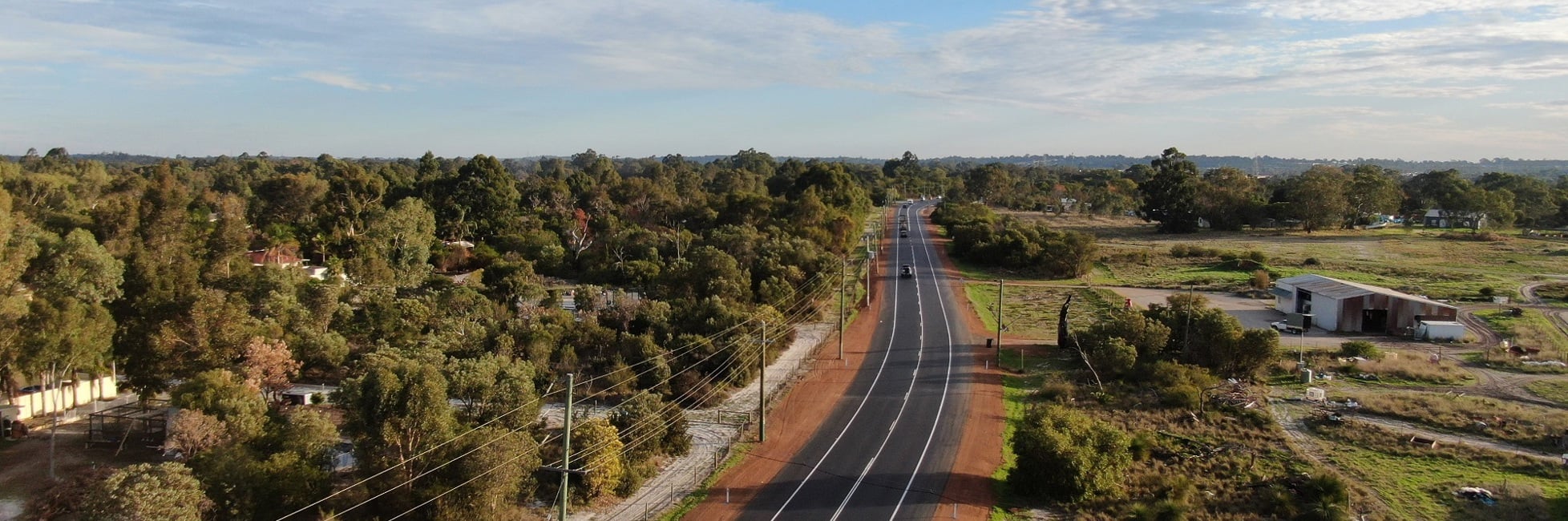 Thomas Road aerial view with trees along one side and a property on the other