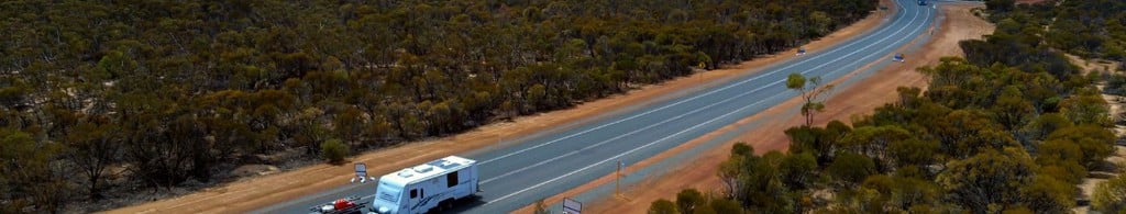 Car with a caravan driving along a regional road
